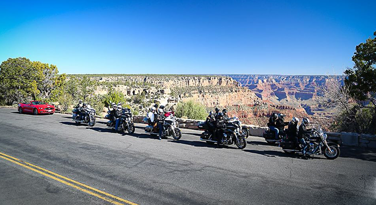 Pessoas de moto na estrada em frente ao Grand Canyon